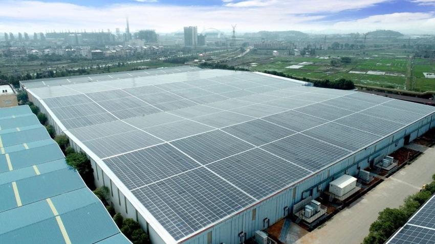 Factory roof covered with solar panels, urban-rural background.